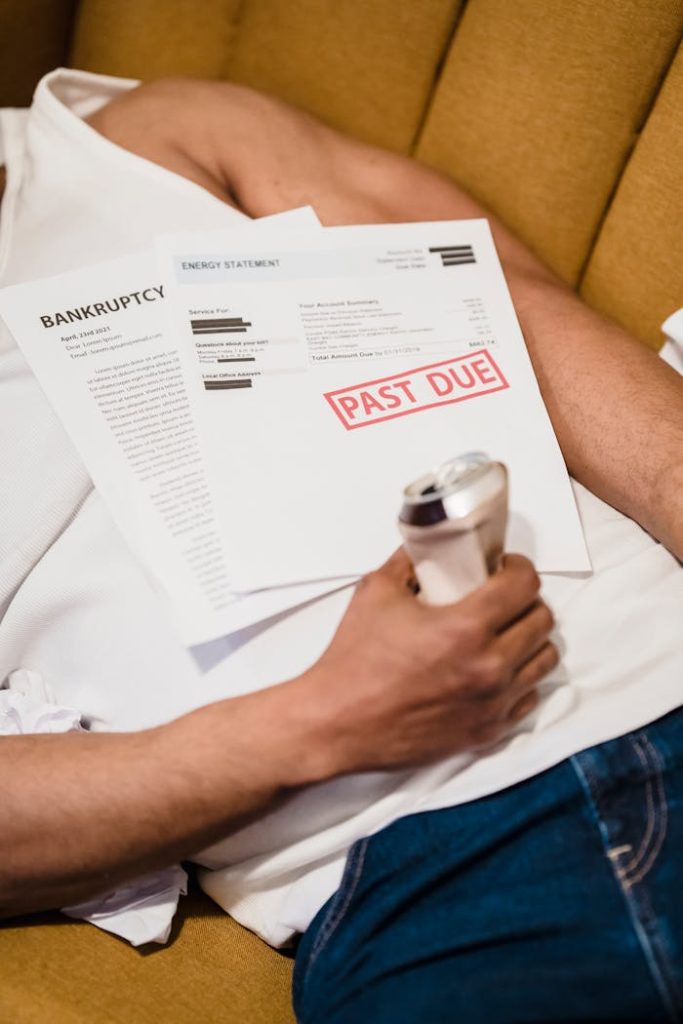 Crafting Captivating Headlines: Your awesome post title goes here Man holding bills labeled Past Due and a drink can, lying on a sofa.